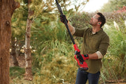 Photo of person using CRAFTSMAN CMCCSP20B cordless pole saw to trim tree branches outdoors.