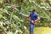 Photo of person using Craftsman pole saw, SKU CMCCSP20B, in the garden to trim tree branches.