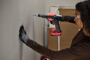 Photo of a person using a Craftsman cordless drill CMCF600B to drive screws into drywall.