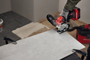 Photo of Craftsman cordless tile saw CMCM300B cutting a large gray tile on a workbench in an indoor setting.