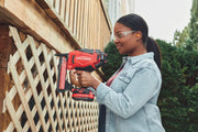 Photo of person using CRAFTSMAN cordless nailer CMCN618NB to fasten wood lattice outdoors, product in side view.