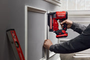 Photo of a person using a Craftsman cordless nailer, SKU CMCN623C1, for trim installation on a wall, indoor setting.