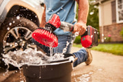 Photo of Craftsman CMCPS520D1 power scrubber with red brush in use outdoors, splashing water into a black bucket.