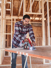 Photo of a person using a Craftsman CMCS550B circular saw to cut plywood on a construction site.
