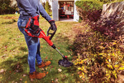 Photo of person using CRAFTSMAN string trimmer, SKU CMCST900B, in a garden near bushes, with tools visible in a shed.