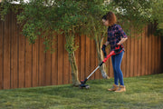 Photo of person using Craftsman string trimmer CMCST900D1 on lawn near trees and wooden fence.