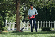 Photo of Craftsman CMCST915D1 string trimmer in use outdoors near a tree and white fence.