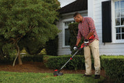 CRAFTSMAN string trimmer CMCST920B being used on lawn near house and hedges outdoors.