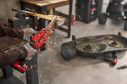 Photo of Craftsman CMCW211B cordless angle grinder in use, grinding metal with visible sparks in a workshop setting.