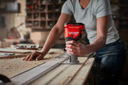 Photo of a person using a Craftsman handheld router, SKU CMCW400B, on a wooden board in a workshop.