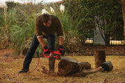 Person using CRAFTSMAN CMECS600 electric chainsaw to cut a log outdoors, red and black tool visible.