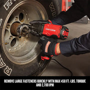 Photo of Craftsman CMEE100 impact wrench in use removing a wheel lug nut, red and black tool held with gloves.