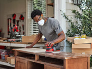 Photo of CRAFTSMAN CMEW231 red orbital sander in use on wood in workshop setting.