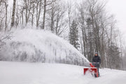 Photo of CRAFTSMAN snow blower CMGB223101 clearing snow outdoors in a snowy, wooded area.