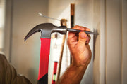 Photo of Craftsman nail set tool CMHT58116 in use, striking a nail with a red-handled hammer.