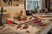 A set of CRAFTSMAN screwdrivers with red and black handles arranged on a woodworking bench, surrounded by wooden boards
