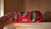 Photo of a red Craftsman torpedo level, SKU CMHT82391, being used to check a shelf's alignment against wood paneling.