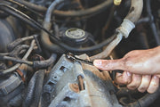 Photo of a hand using a CRAFTSMAN wrench, SKU CMMT87707, to tighten a bolt on an engine in a workshop setting.
