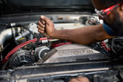 Photo of CRAFTSMAN wrench SKU CMMT99154L turning bolt in car engine bay, mechanic's hand visible.