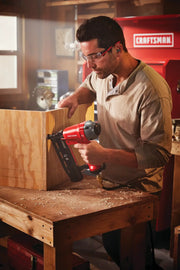 Photo of CRAFTSMAN CMPFN16K finish nailer used on wood panel in workshop setting.