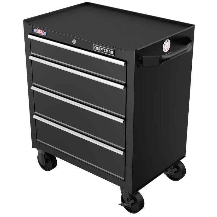 Black rolling tool chest with four drawers, silver handles, and wheels. The top surface is flat and textured, and there are labels visible on the front and side.