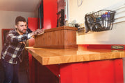 Photo of Craftsman CMST27200R wooden workbench top in workshop setting with red cabinets and wall storage baskets.