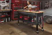 Photo of Craftsman workbench CMST27202BK with wood top, storage drawers, wheels, and tools in a garage workshop.