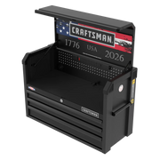 A black Craftsman tool chest with its top compartment open, showing the American flag design and the numbers 1776 and 2026 on the back panel. The unit features a pegboard section, multiple power outlets, and three lower drawers.