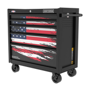 A black rolling tool chest with four drawers, featuring a stylized American flag design on the front. The chest has wheels for mobility and a handle on the side. The brand 'CRAFTSMAN' is visible at the top.