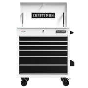 A white and black Craftsman tool chest with multiple drawers and caster wheels. The top compartment is open, displaying the Craftsman logo, and there is a small USA flag decal on the upper left.