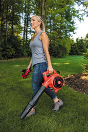Photo of a person carrying a red Craftsman handheld leaf blower, SKU CMXGAAM204101, in a grassy yard.