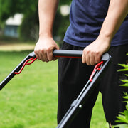 Close-up of a person holding the handle of a lawn mower, with green grass visible in the background.