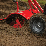 Photo of CRAFTSMAN tiller CMXGVAM1144037 in action, red metal body, churning soil with rugged tire visible.