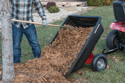 Photo of CRAFTSMAN dump cart SKU CMXGZBF7124489 unloading mulch onto grass, attached to a red lawn tractor.