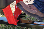 Photo of a boot pressing a Craftsman CMXGZBF7124489 foot pedal on red metal equipment, close-up outdoor view.