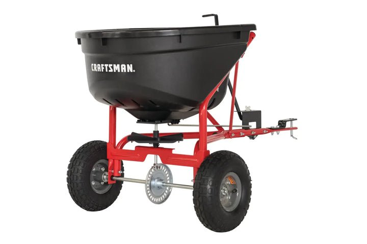 Front angle photo of Craftsman tow-behind spreader, black hopper and red frame, SKU CMXGZBF7124571.