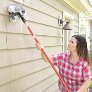 Photo of CRAFTSMAN CMXMLBA7210A cleaning brush with red pole used to scrub beige house siding.