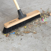 Photo of Craftsman broom CMXMLBA7218A sweeping leaves and debris on concrete floor.