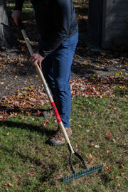 Photo of a person using a Craftsman garden rake, SKU CMXMLTP35317, on a grassy lawn with fallen leaves.