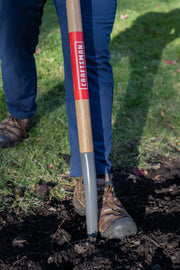 Photo of CRAFTSMAN digging shovel CMXMLTP35327 with wood handle and gray blade in use on garden soil.