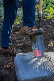 Photo of CRAFTSMAN shovel CMXMLTP35329 with a boot pressing the blade into a bag of soil in a garden.