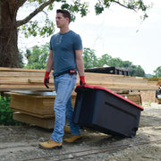 Photo of a person pulling a CRAFTSMAN rolling storage bin, SKU CMXXPBP50GTW, with black body and red lid at a construction site.