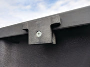 Photo of Craftsman CMXZBAD29510601 black plastic latch on textured surface, close-up outdoor angle.
