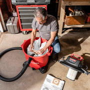 Photo of Craftsman wet/dry vacuum, SKU CMXZVBE38749, with person installing dust bag in open red canister in workshop.