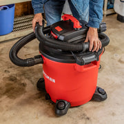 Photo of a CRAFTSMAN wet/dry vacuum, SKU CMXZVBE38763, red and black, shown in a garage with person handling hose.