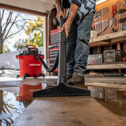 Photo of Craftsman CMXZVBE38778 wet/dry shop vacuum cleaning a water spill in a garage workshop.