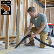 Craftsman jobsite vacuum hose in use, model CMXZVBE38800, cleaning sawdust from construction area floor.