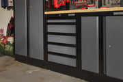 A black and gray Craftsman storage cabinet with five drawers, placed in a garage workspace alongside other storage units and a wooden countertop.